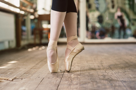 Feet of ballerina dancing in ballet shoes. Ballerina standing on toes