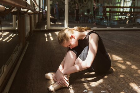 Young ballet dancer practicing in class. Ballerina doing exercises. Girl stretches herself in the dancing hall.の写真素材
