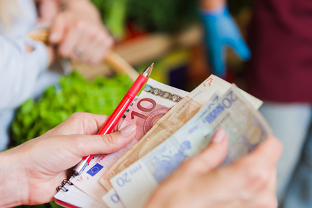 Young woman holding money to pay for her vegetablesの写真素材