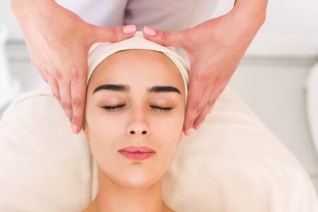 Facial massage beautiful girl. Portrait of a girl in a massage parlor. Beautician doing massage of female faces. Massage face girl close-up.の写真素材