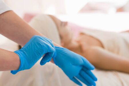 Doctor wears blue gloves. Woman patient in the backgroundの写真素材