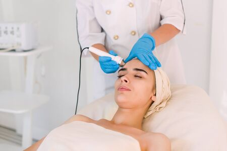 Young healthy woman with good skin doing cosmetic procedures in spa clinic.の写真素材