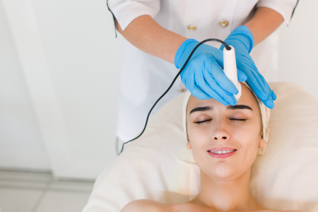 Young healthy woman with good skin doing cosmetic procedures in spa clinicの写真素材
