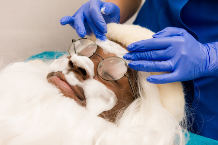 Black santa claus in beauty spa. Spa facial mask application. Spa beauty organic facial mask application at day spa salon.の写真素材