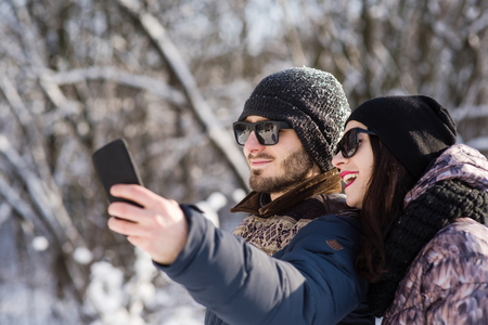 Smiling couple making selfie in winter outdoorsの写真素材