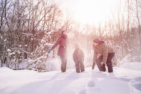 Happy family throw snow at sunset in winter forestの写真素材