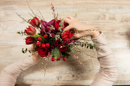 Female hands arrange red bouquetの写真素材