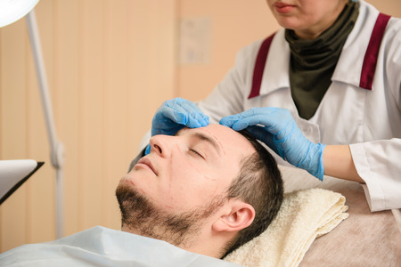 Hands of doctors in blue gloves touch faceの写真素材