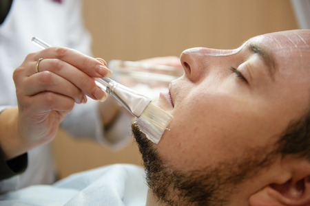 Close-up of applying a face mask to young manの写真素材