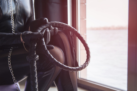 Woman in total black leather look with lash in her handsの写真素材