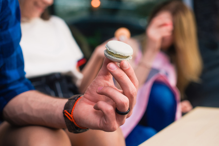 Sweet dessert cookie in male hands on bokeh background. Boy hold green macaron close up.の写真素材
