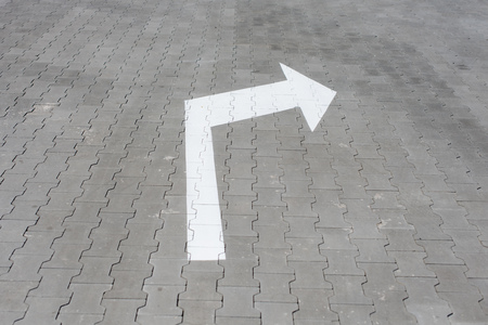 White arrow down on street tile. Sign for pedestrians show the way left