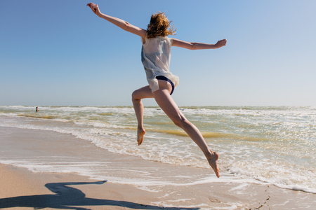 View of happy female from back jumping in swimwear.の写真素材