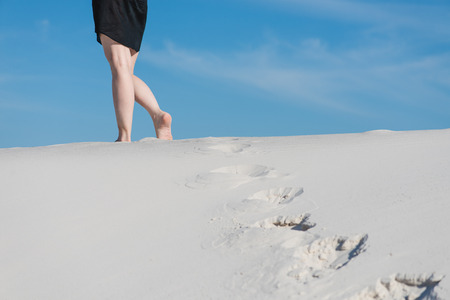 Female legs and prints on white sandの写真素材