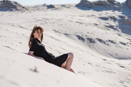 Attractive young female lay at desert dunesの写真素材
