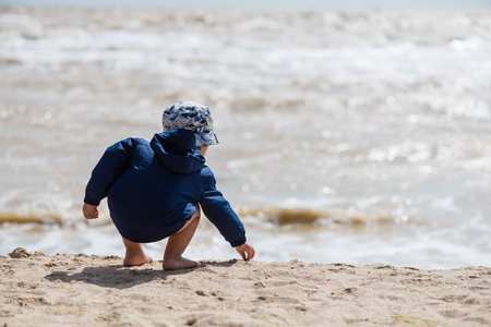 Toddler in panama and jacket at beachの写真素材