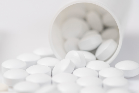 White pills spilling out of toppled pill bottleの写真素材