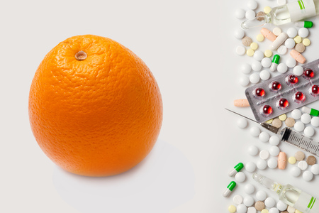 One orange and heap of pills. White background.の写真素材