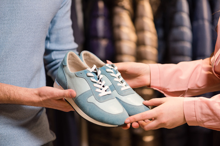 Hands hold dark green suede moccasins close up.の写真素材