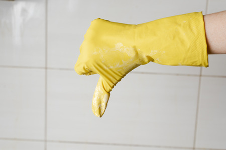 Hand in yellow rubber glow showing thumb downの写真素材