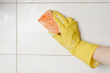 Close-up woman cleaning tiled surface in kitchen.の写真素材