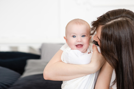 Mother hugs smiling little daughter, close up.