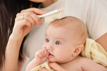Female hand combing hair baby, close up.の写真素材