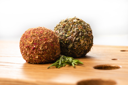 Close-up of two soft cheese balls labne with spices on wooden board.