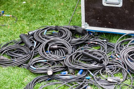 Many coiled black electrical wires at grass