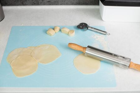 Process of rolling and cutting raw dough with pastry mat, cutter, pin on table, cooking at home...
