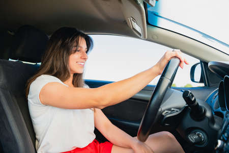 Brunette woman sit inside car salon, hold hands on steering wheel, going to drive, female happy...