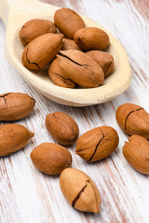 Pecans in a wooden spoon on a wooden background. Close-up. Pecan in shell.
