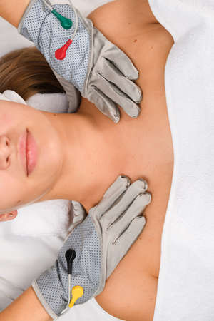 Hardware cosmetologist in gray microcurrent gloves for myostimulation therapy put hands on female client shoulders, up view.の写真素材