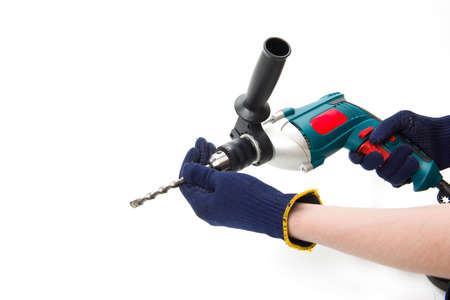 Man in protective gloves change drill in electric perforator at cut out isolated background, construction, renovation, repair toolの写真素材