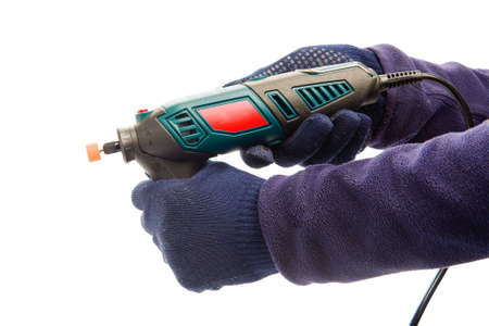 Two male hands in navy blue protective gloves holding perforator with nozzle for grinding and polishing at isolated white background.の写真素材