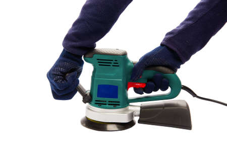 Man in protective blue gloves hold handles of eccentric orbital sander machine at isolated white backgroundの写真素材