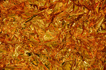 Gold foil background with shiny crumpled surface for texture backgroundの写真素材