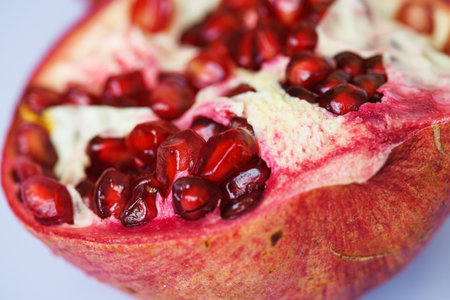 Macro of garnet pomegranate red fruit with peel and seeds at isolated background, healthy vegetarian...