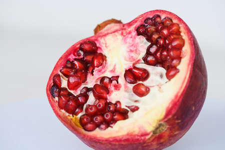 One open half of ripe pomegranate garnet fruit with peel and seeds at isolated background, healthy food and drink ingredientの写真素材