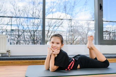 Preteen female child relax at floor mat in black leggings and top after yoga, fitness, gymnastics training, sport fashion and healthy childhood hobbyの写真素材