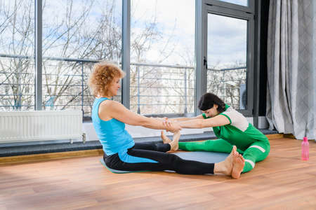 Two mature sport women stretch each otherの写真素材