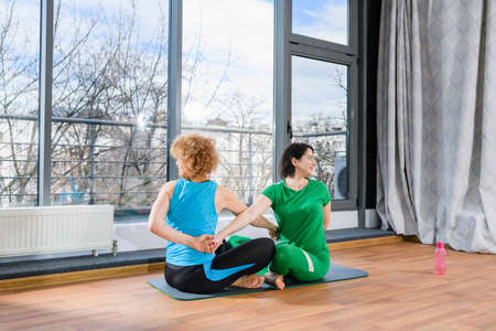 Two women exercise yoga with crossed hands