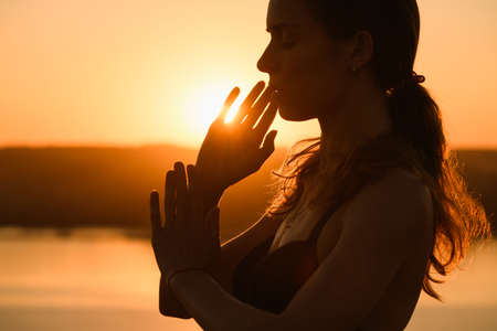 Beautiful girl portrait raise hands and face close up in warm sun light outdoor, yoga meditation practiceの写真素材