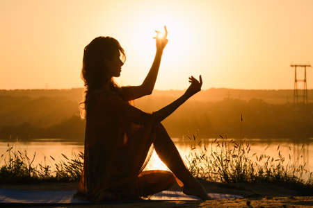 Beautiful girl silhouette in warm sunrise lightの写真素材