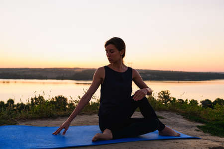 Yoga woman stretching at golden sunrise outdoorsの写真素材