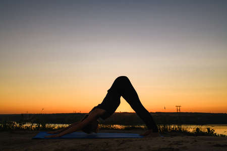 Silhouette of fit yoga woman stretching outdoorsの写真素材