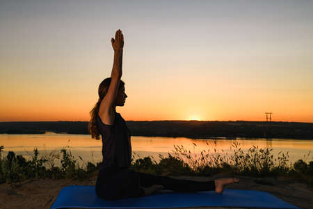 Woman stretching outdoor at sunrise warm lightの写真素材