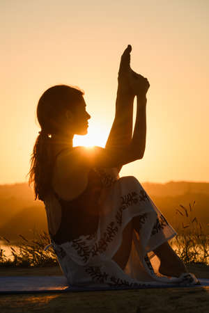 Female silhouette stretching at warm sun lightの写真素材