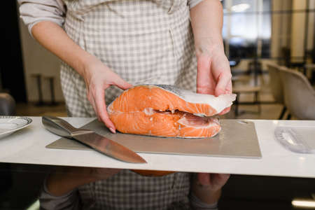 Raw red salmon fish slice in Caucasian woman hands, close up.の写真素材
