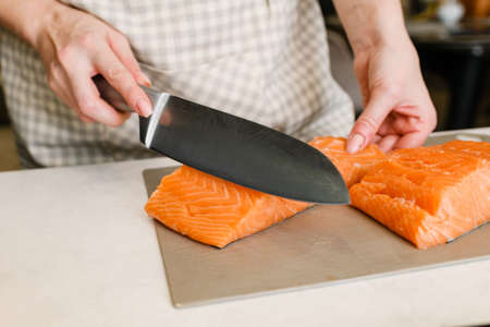 Hand cutting steaks of salmon to prepare for cooking and consumption.の写真素材